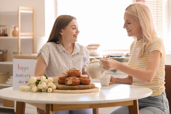 Kızıyla birlikte mutfakta çay içen olgun bir kadın. Anneler Günü kutlaması