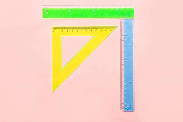 ピンクの背景にカラフルなストレートと三角形のプラスチック定規 — ストック写真