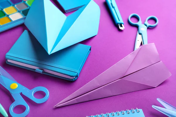 Composition with stationery supplies and paper planes on purple background