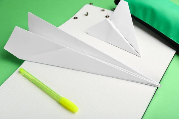 Composition with stationery supplies and paper planes on green background