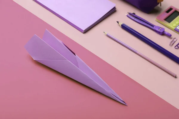 Composition with stationery supplies and paper plane on pink background