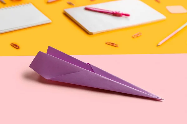 Composition with stationery supplies and paper plane on color background