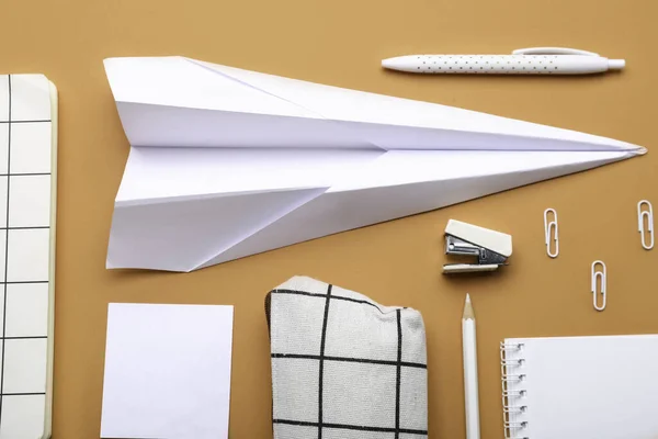 Composition with stationery supplies and paper plane on orange background