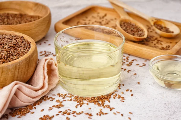 stock image Glass and bowl with flax oil and seeds on light background