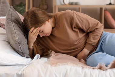 Yatak odasında apandisiti olan genç bir kadın yatıyor.