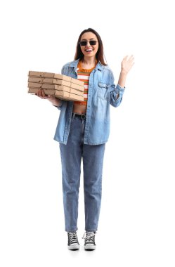 Beyaz arka planda karton pizza kutularıyla güneş gözlüklü genç bir kadın.