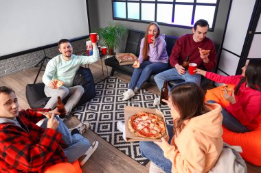 Evde lezzetli pizzaları ve içkileri olan bir grup arkadaş
