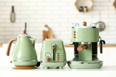 Elektrik ısıtıcısı, kahve makinesi ve ekmek kızartma makinesi mutfaktaki masada.