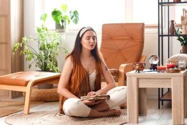 Evde büyü kitabıyla meditasyon yapan falcı.