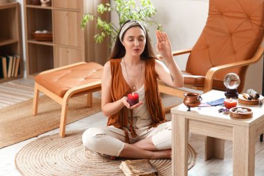 Mumlu genç cadı evde meditasyon yapıyor.