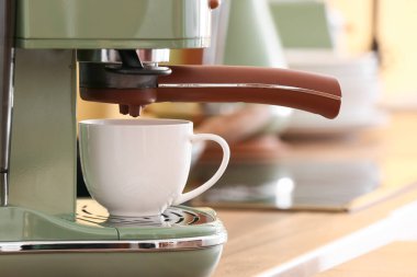 Mutfak tezgahında fincanı olan modern kahve makinesi, yakın plan.