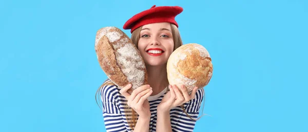 Szczęśliwa Młoda Kobieta Bochenkami Świeżego Chleba Niebieskim Tle — Zdjęcie stockowe