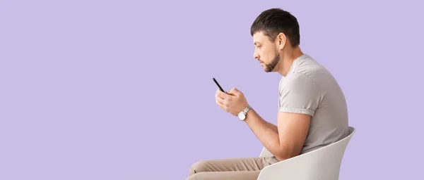 Man with bad posture using mobile phone while sitting on chair against lilac background