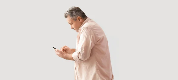 Älterer Mann Mit Schlechter Körperhaltung Mit Handy Auf Hellem Hintergrund — Stockfoto