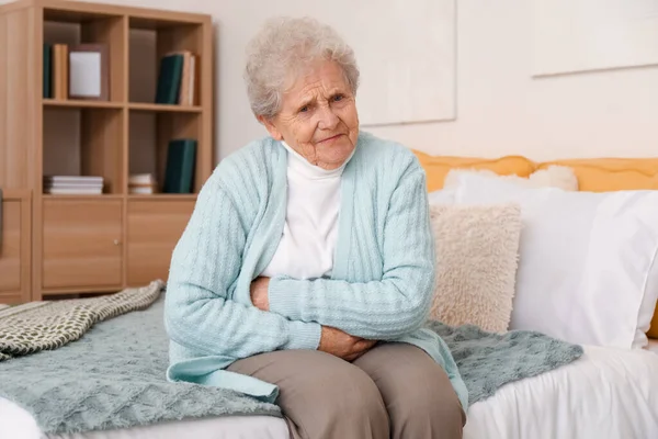 患阑尾炎的老年妇女坐在卧室里 — 图库照片