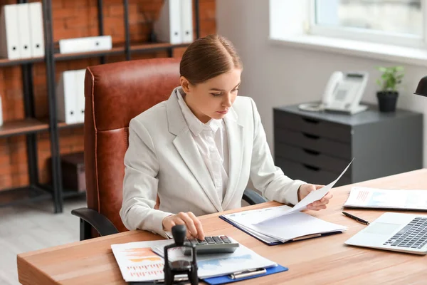 事務所のテーブルで計算機や書類を扱う女性会計士 — ストック写真