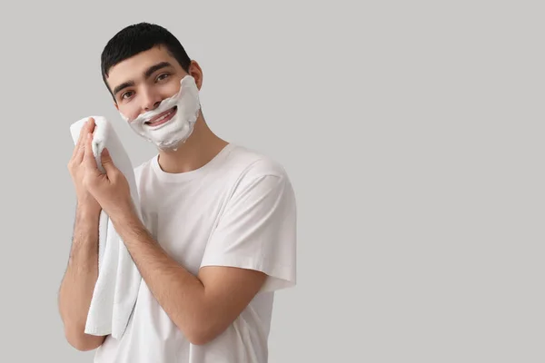 Jovem Limpando Espuma Barbear Rosto Contra Fundo Claro — Fotografia de Stock