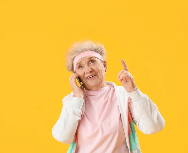 身材矮小的老年妇女在黄色背景下用手机交谈 — 图库照片