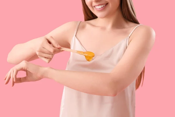 若いです女性適用Sugaringペーストに彼女の腕にピンクの背景 — ストック写真