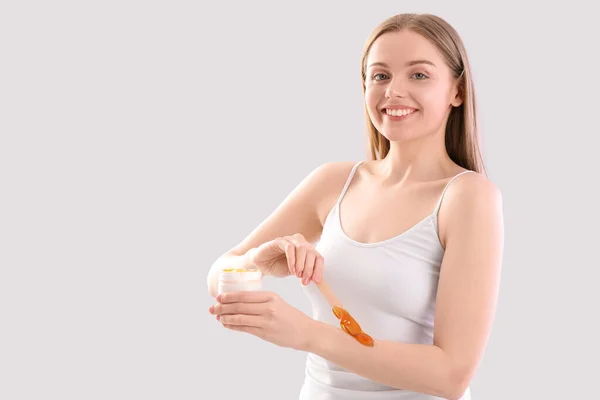 stock image Young woman applying sugaring paste onto arms against light background