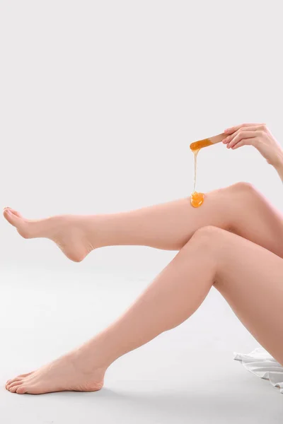 Młoda Kobieta Nakładająca Pastę Cukrową Nogi Jasnym Tle — Zdjęcie stockowe