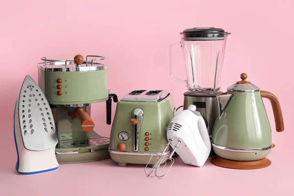 Set of modern household appliances on pink background