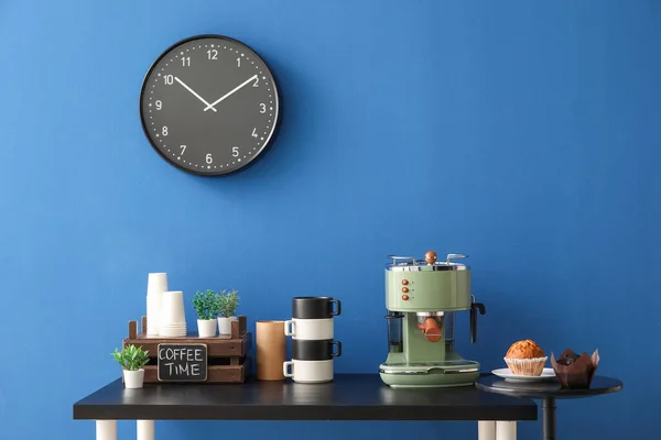 Modern Kahve Makinesi Muffinler Fincanlar Mavi Duvarın Yanındaki Siyah Masada — Stok fotoğraf