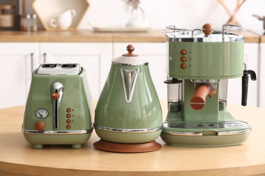 Kahve makinesi, tost makinesi ve elektrikli su ısıtıcısı mutfaktaki masada.