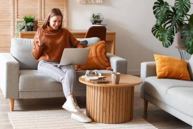 Evdeki kanepede dizüstü bilgisayar kullanan bir kız öğrenci.