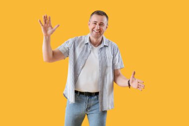 Sarı arka planda kucaklaşmak için kollarını açan olgun bir adam. Merhaba konsept