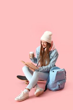 Pembe arka planda kahve fincanı okuyan bir kız öğrenci.