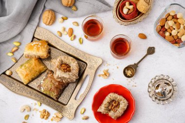 Lezzetli baklava tepsisi ve arka planda bir bardak Türk çayı.