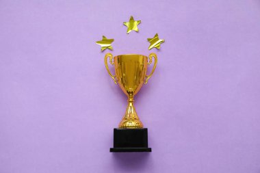 Leylak arka planında yıldızlar olan altın kupa