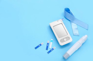 Mavi arka planda glukometre ve tükenmez kalemle farkındalık kurdelesi. Diyabet kavramı