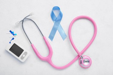 Beyaz arka planda glukometre ve steteskop ile farkındalık kurdelesi. Diyabet kavramı