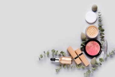 Gri arkaplanda okaliptüs dallarıyla dekoratif kozmetikten yapılmış çerçeve