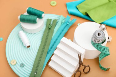 Turuncu arka planda terzi malzemesi olan podyumlar