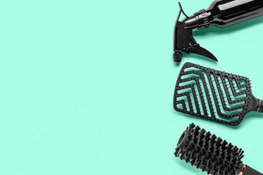 Turkuaz arka planda spreyli kuaför fırçaları.