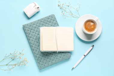 Mavi arka planda defter, kahve ve kulaklık ile kompozisyon