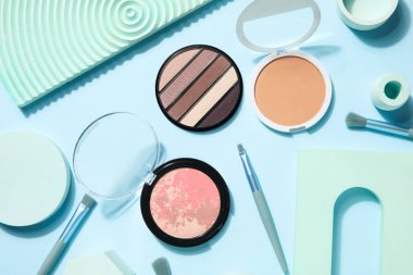 Mavi arka planda fırçalar ve podyumlarla dekoratif kozmetikler