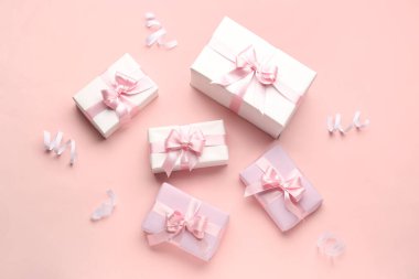 Güzel fiyonklu hediye kutuları ve pembe arka planda yılan.