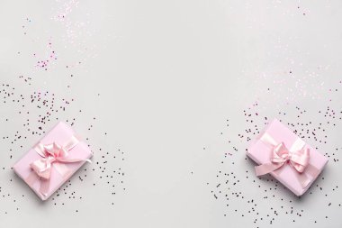 Güzel fiyonklu hediye kutuları ve gri arka planda konfeti.