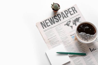 Kahveli gazete, yapışkan notlar, beyaz arka planda kalem ve kaktüs, yakın plan.