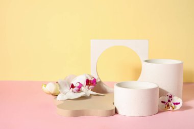 Dekoratif alçı podyumlar ve güzel orkide çiçekleri pembe masada bej arka planda.