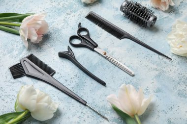 Mavi masanın üzerinde kuaför aletleri ve lale çiçekleri olan kompozisyon