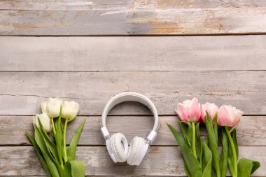Modern kulaklıklı kompozisyon ve ahşap arka planda güzel lale çiçekleri.