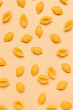 Sarı arkaplanda çiğ konchiglie makarna