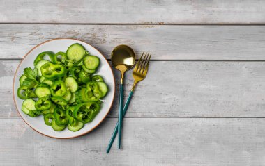 Gri ahşap arka planda yeşil sebzeli bir tabak salata.