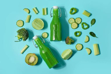 Turkuaz arka planda lezzetli yeşil meyve suyu ve malzemeler var.