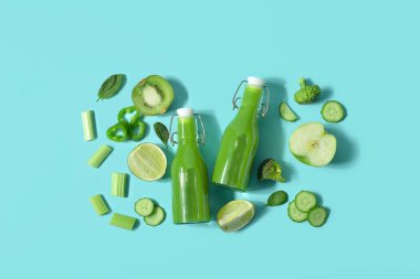 Turkuaz arka planda lezzetli yeşil meyve suyu ve malzemeler var.